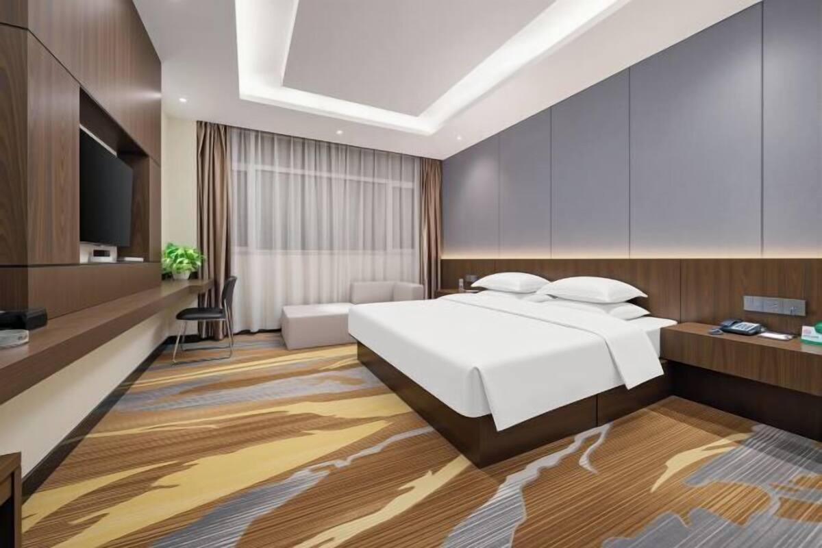 Une chambre d’hôtel moderne équipée d’un grand lit, d’un bureau, d’une télévision et d’un coin salon.