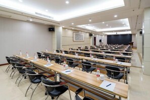 Une salle de conférence dotée de plusieurs tables et chaises, ainsi que de bouteilles d’eau et de plaques nominatives.