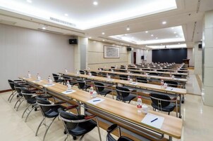 Un salón de conferencias con varias mesas y sillas, equipado con botellas de agua y tarjetas de identificación.