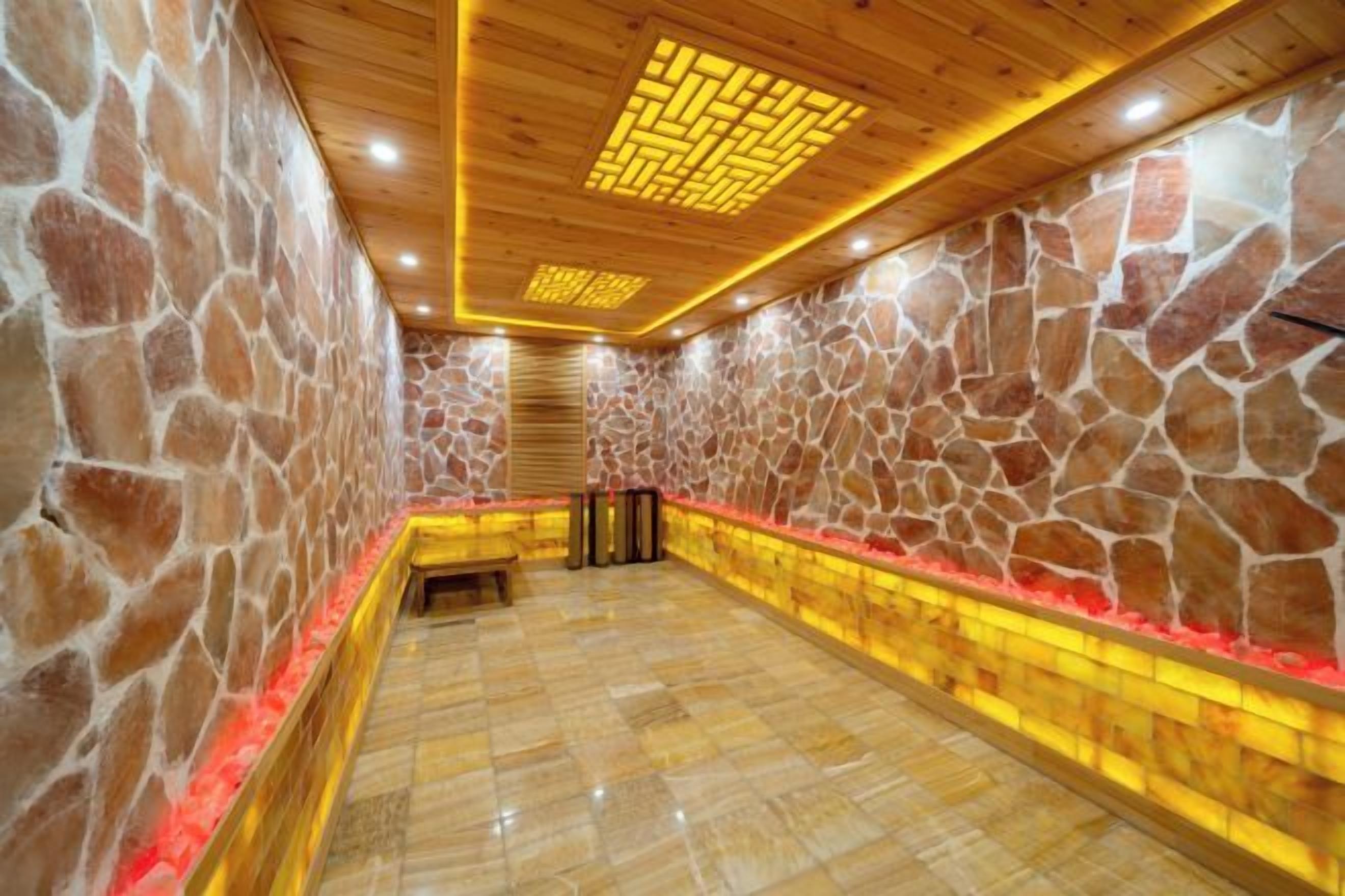 A stone-walled sauna with a wooden ceiling and a tiled floor.