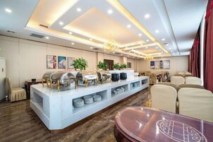Comedor de hotel con mesas dispuestas, barra de buffet y candelabro.