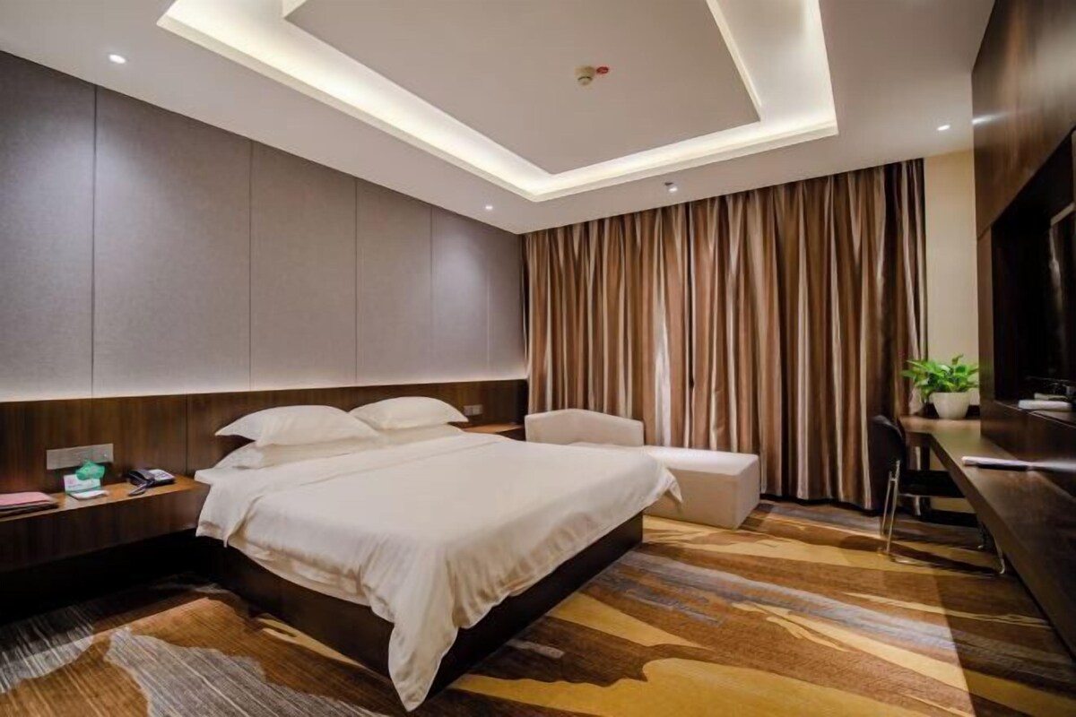 Ein modernes Hotelzimmer mit einem großen Bett, einem Schreibtisch und einem Sessel.