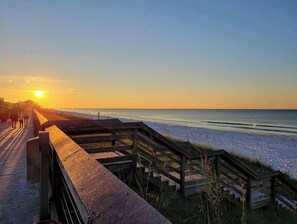 A wooden boardwalk leading to a beach with the sun setting in the background. - Spacious 4 Bedroom / 3 Bath beach condo sleeps 12 (Miramar Beach)