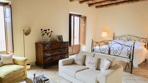A cozy living room with a sofa, a wooden dresser, and a bed with a metal frame. - Charming Bed and Breakfast in Castiglione di Sicilia (Castiglione di Sicilia)