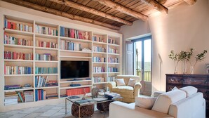 A spacious living room with a large bookshelf, a flat-screen TV, and a comfortable seating area. - Charming Bed and Breakfast in Castiglione di Sicilia (Castiglione di Sicilia)