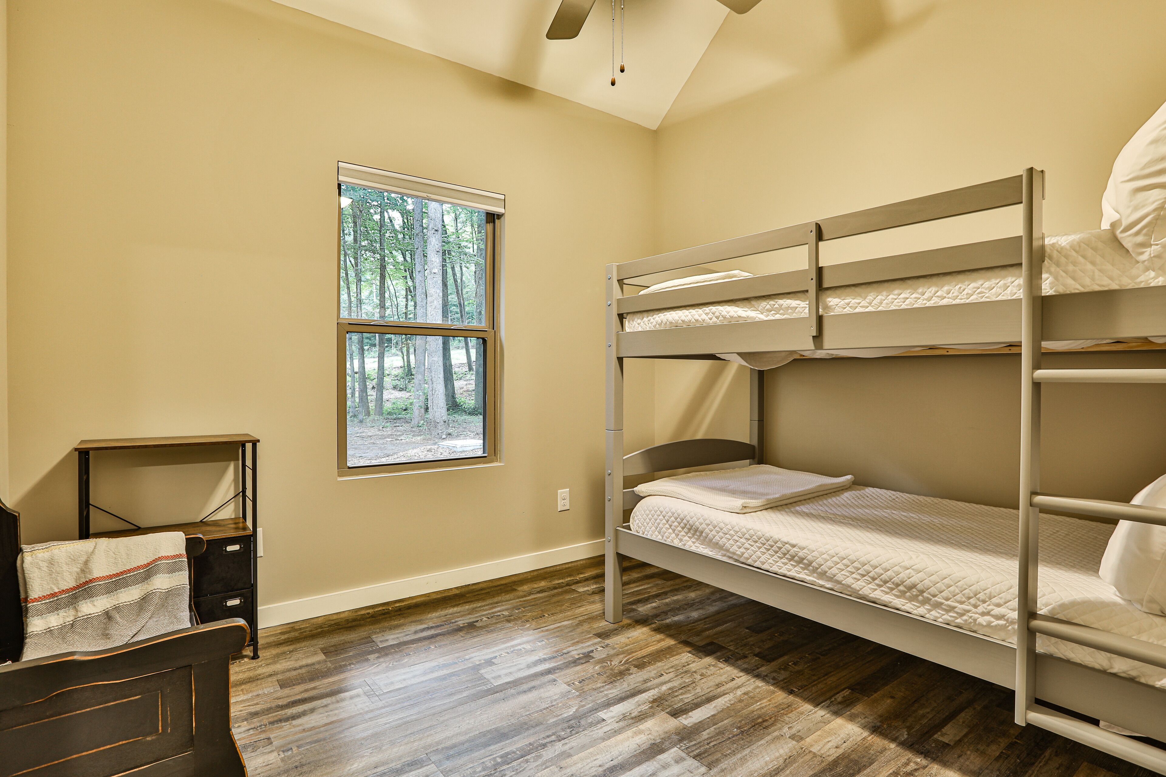 A bunk bed room with a window, a desk, and a chair.