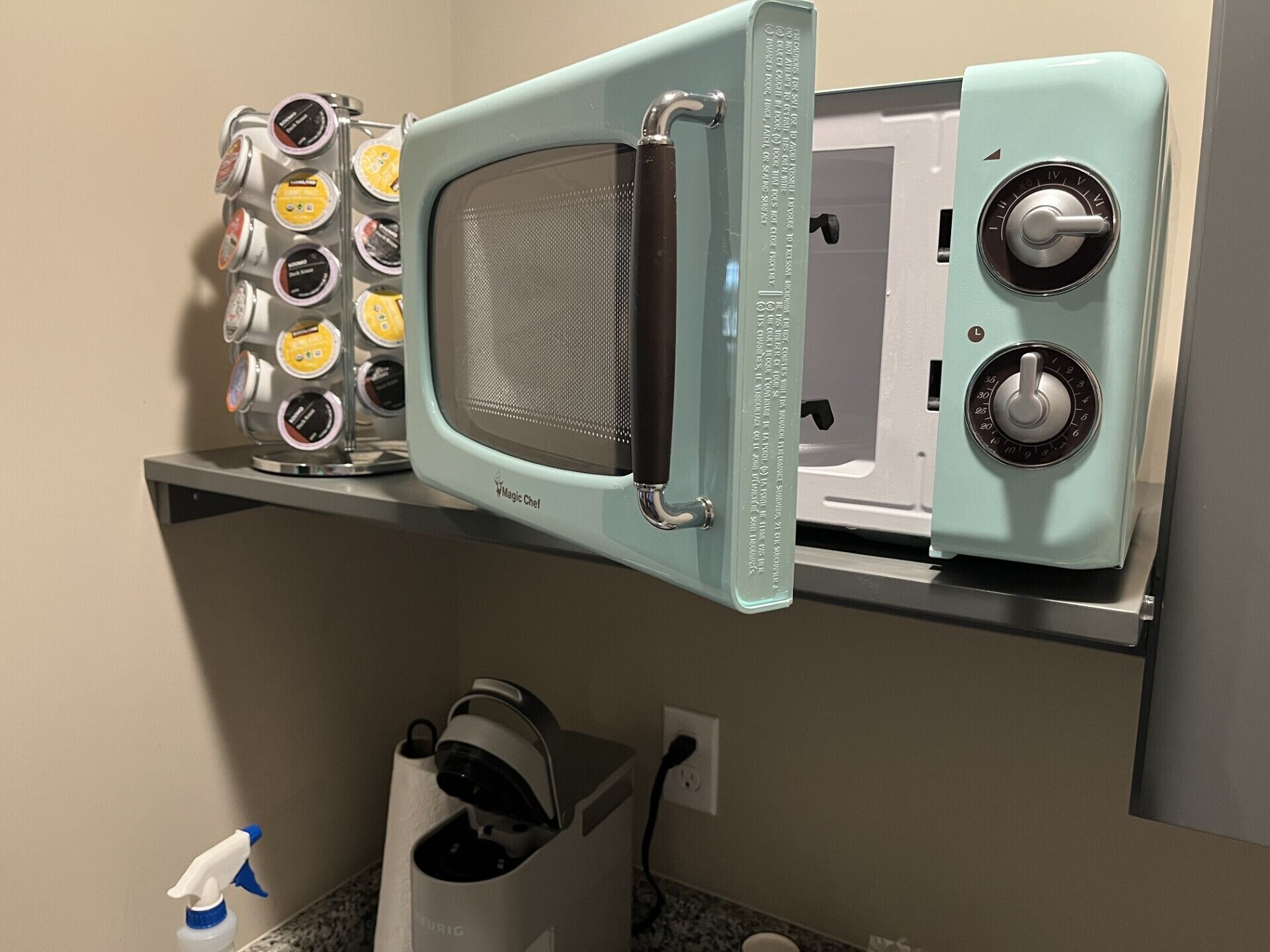 A kitchen with a microwave, a coffee maker, and a shelf with various containers.