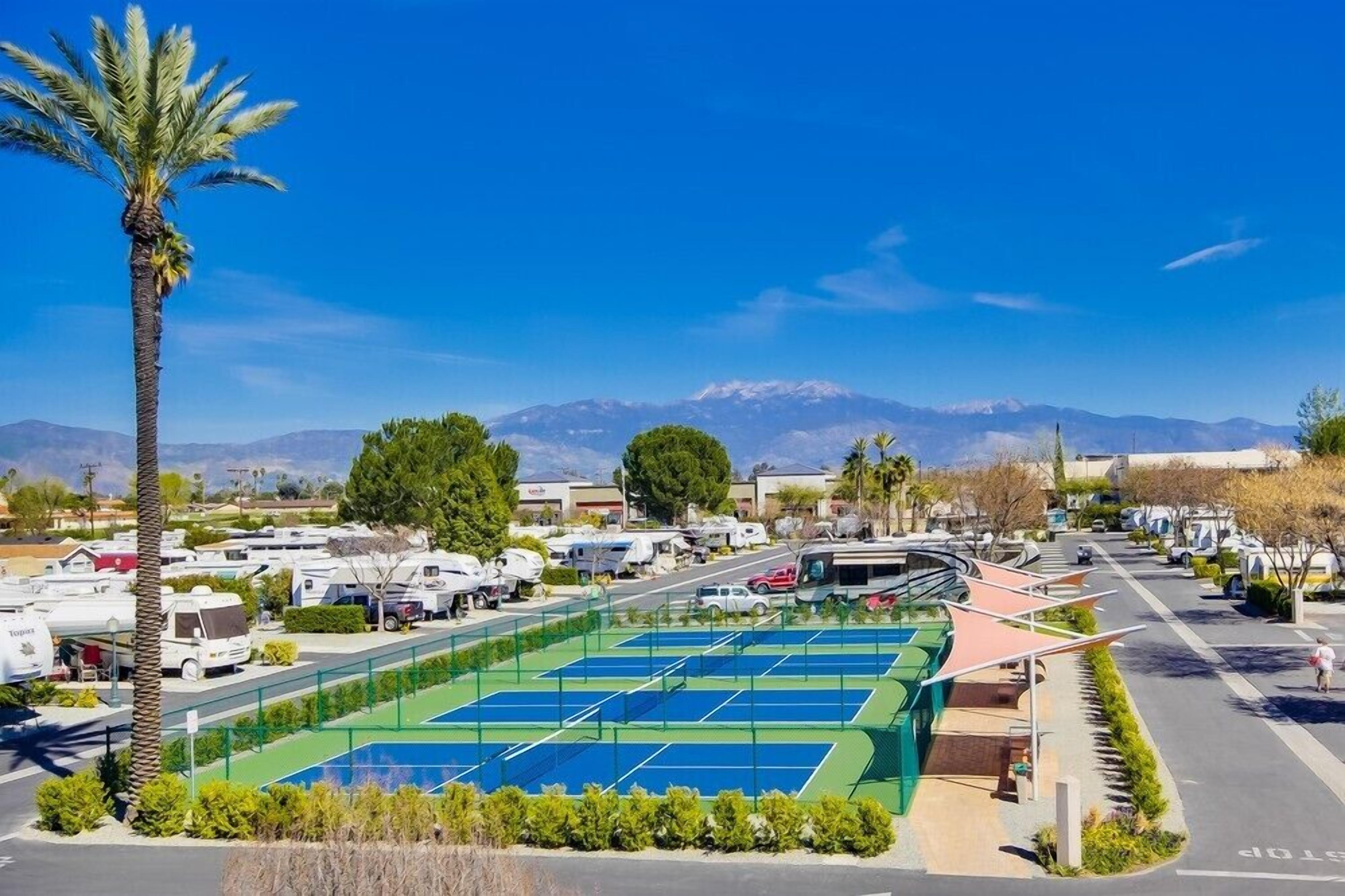 Un parcheggio con camper e un campo da tennis.