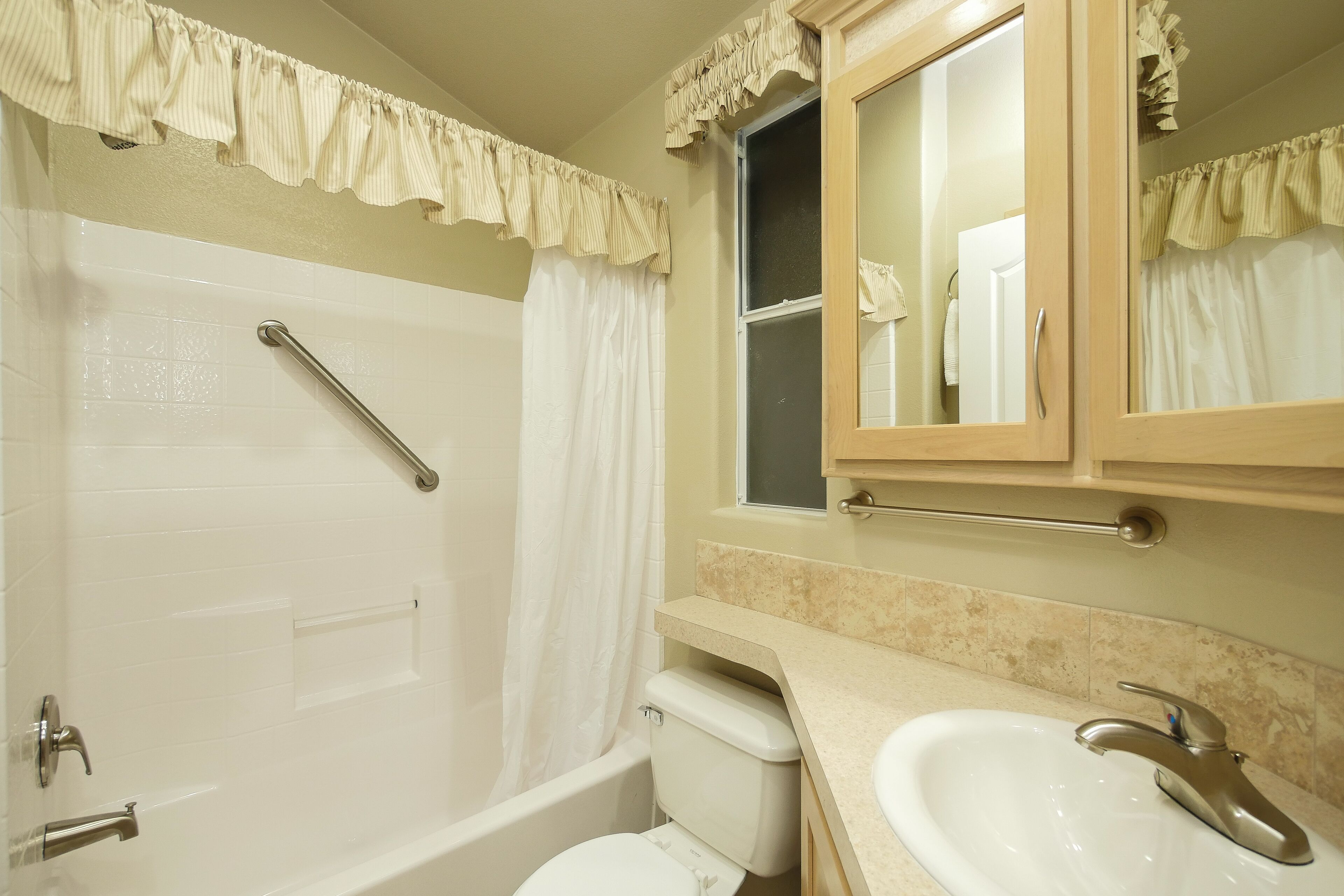 A bathroom with a bathtub, toilet, sink, and mirror.