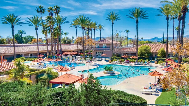 Un complexe hôtelier doté de plusieurs piscines, de palmiers et offrant une vue sur un paysage montagneux.