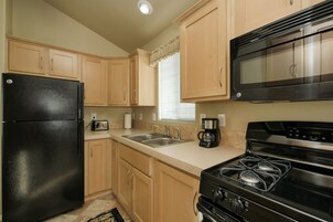 Una cocina con armarios de madera, un refrigerador negro, una estufa y un microondas.
