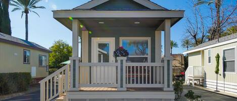 A single-story house with a porch, a small garden, and a vehicle parked outside.