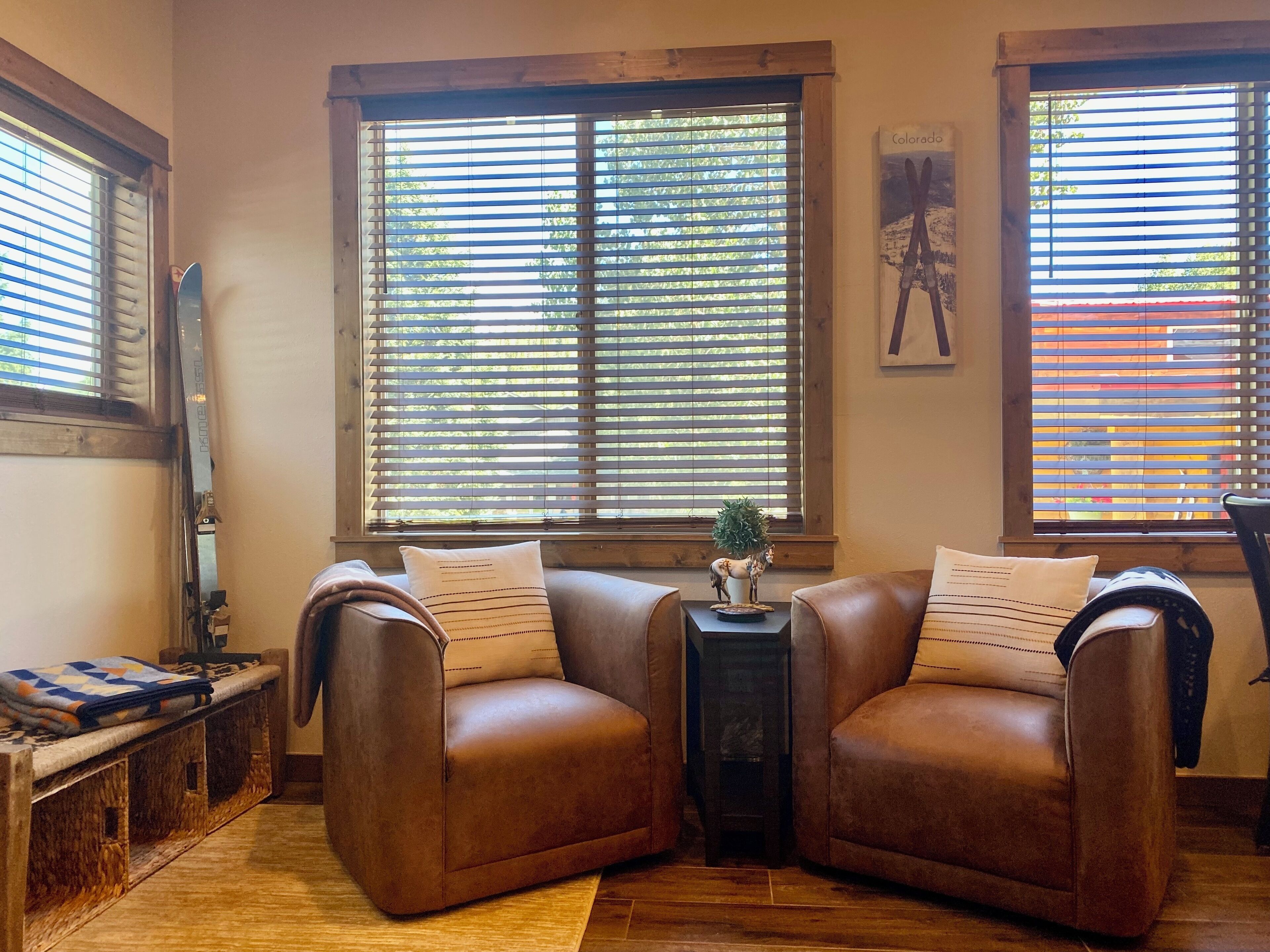 Un salón acogedor con dos sofás de cuero marrón, una mesita auxiliar con un objeto decorativo y una ventana con persianas.