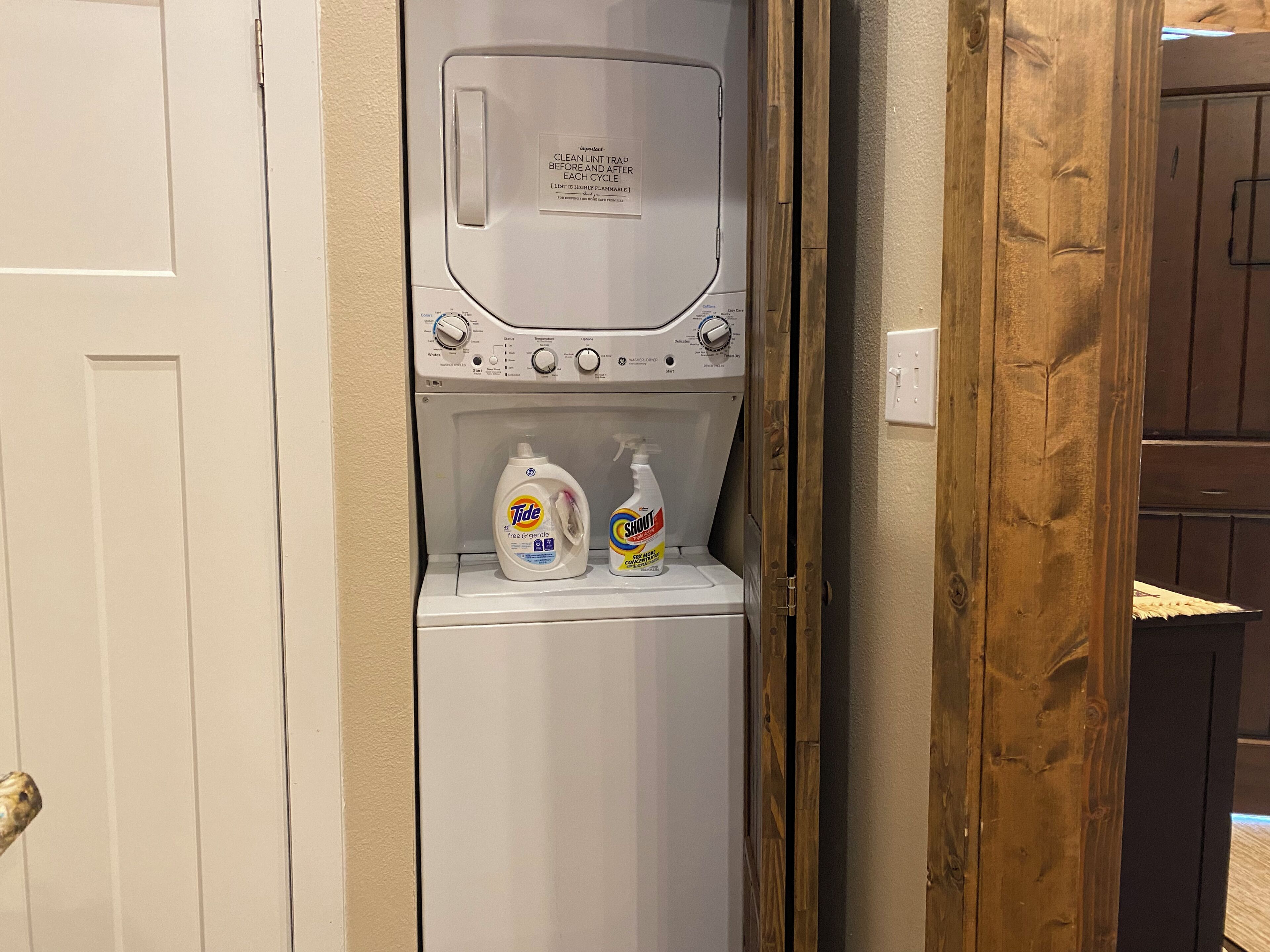 Una lavadora de carga frontal con botellas de detergente Tide y Stout en su interior.