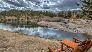 Vista de un lago con un banco de madera y un bosque al fondo.