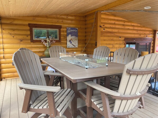 L’intérieur d’un chalet en bois, avec une table à manger, des chaises, un vase de fleurs et une affiche accrochée au mur.