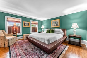 A bedroom with a large bed, two bedside tables, a chair, and a patterned rug. - The Inn On Market (New Wilmington)