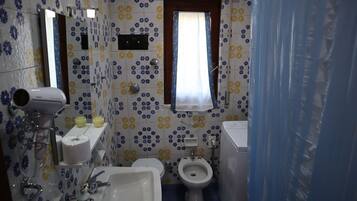 Une salle de bain équipée de toilettes, d’un bidet, d’un lavabo et d’un miroir.