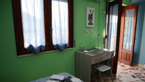 Una habitación con cama, escritorio, silla y ventana con cortinas.