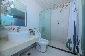 Une salle de bain avec un lavabo blanc, des toilettes, une douche en verre et un miroir.