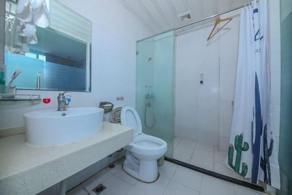 Une salle de bain avec un lavabo blanc, des toilettes, une douche en verre et un miroir.