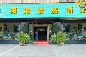 A hotel entrance with a blue sign, potted plants, and a red carpet. - Ningbo Sunshine Yiran Hotel (Ningbo)