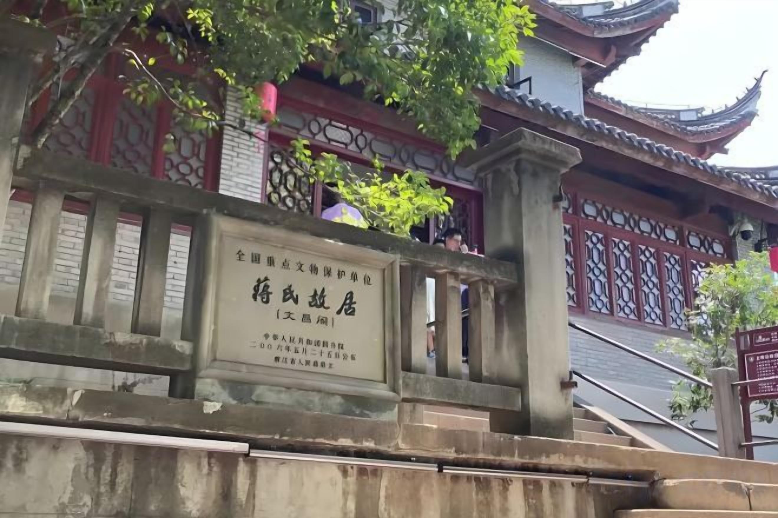 A traditional Chinese gate with a plaque, leading to a building with ornate architecture.