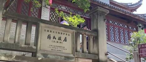 A traditional Chinese gate with a plaque, leading to a building with ornate architecture.