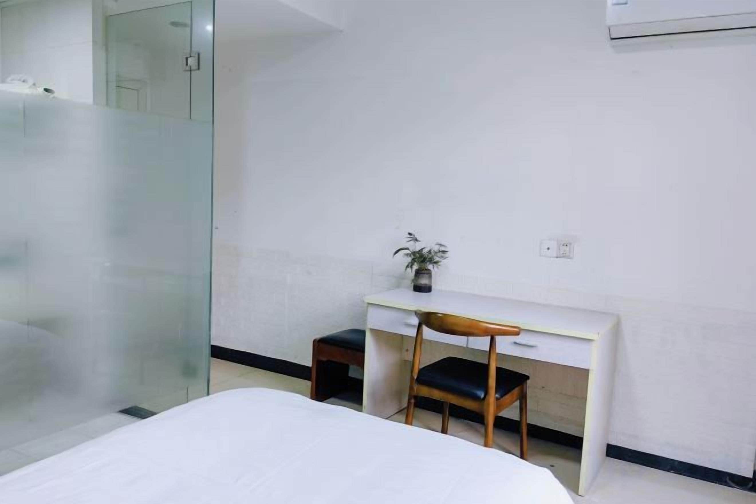 Una habitación de hotel con una cama, un escritorio, una silla y una mesita con una planta.