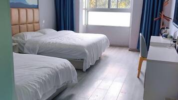 Een hotelkamer met twee bedden, een bureau en een raam met gordijnen.