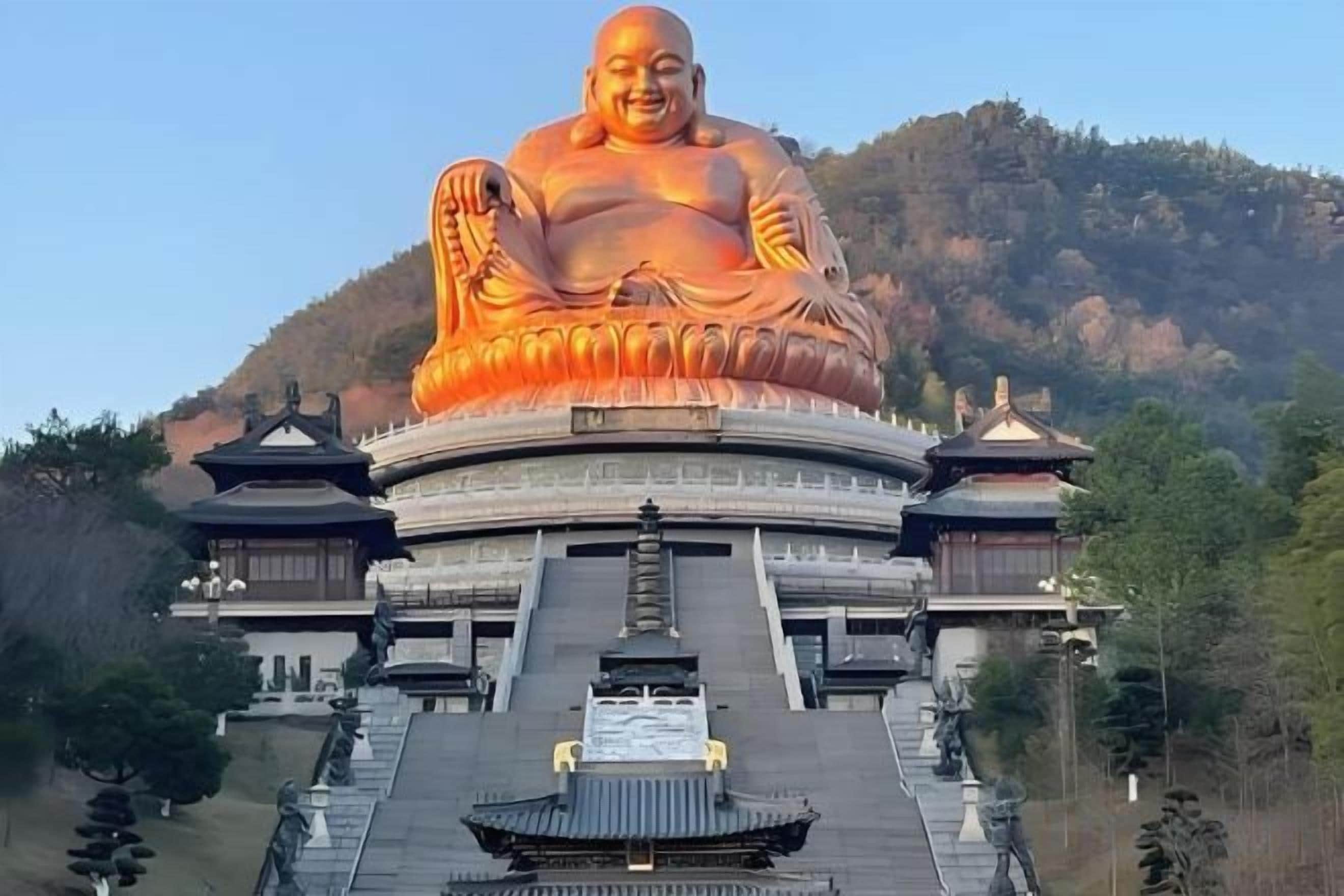 A large seated Buddha statue with a circular base, surrounded by traditional architecture.