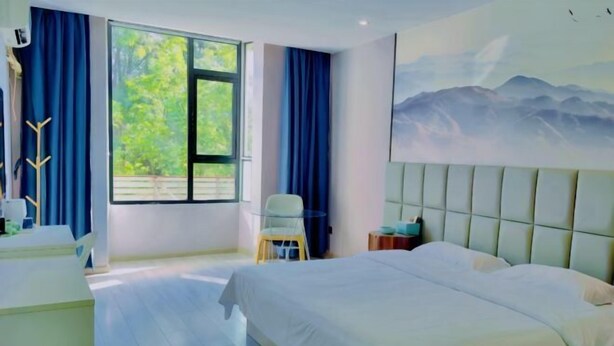 Habitación de hotel con cama, una silla, un escritorio y ventana con cortinas.