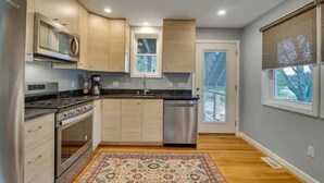 A modern kitchen with wooden cabinets, stainless steel appliances, and a large window.
