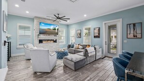 A living room with a fireplace, a ceiling fan, and a TV mounted on the wall.