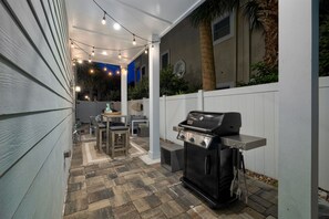 A patio area with a grill, outdoor furniture, and string lights. - Ocean View Bliss | Steps to Beach | Golf Cart Perk (Jacksonville Beach)