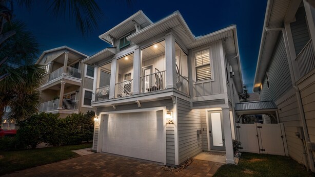 A two-story house with a garage, a balcony, and a well-lit driveway.