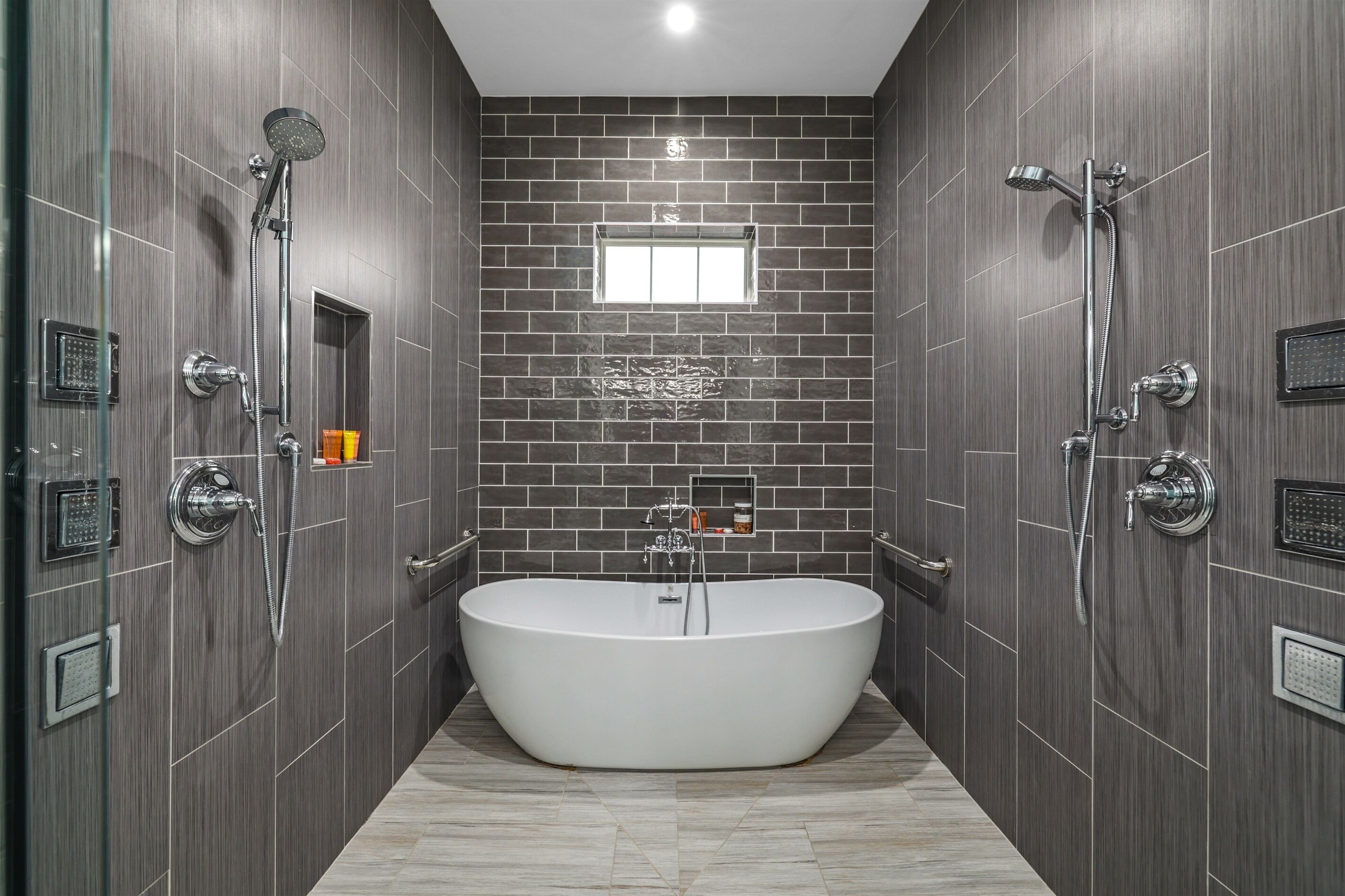 Un baño moderno con una bañera independiente, dos cabezales de ducha y un ventanal.