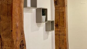Eine Wand mit drei rechteckigen, metallenen Regalen unterschiedlicher Größe, wobei eines ein Blumentopf enthält.