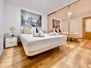 A modern bedroom with a large bed, a nightstand, a mirror, and a cityscape painting on the wall. - Puerta del Sol V - In the center of Madrid (Madrid)
