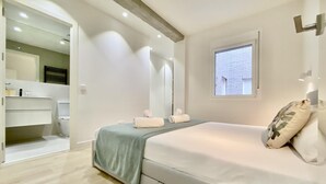 A bedroom with a bed, a window, a bathroom, and a mirror.