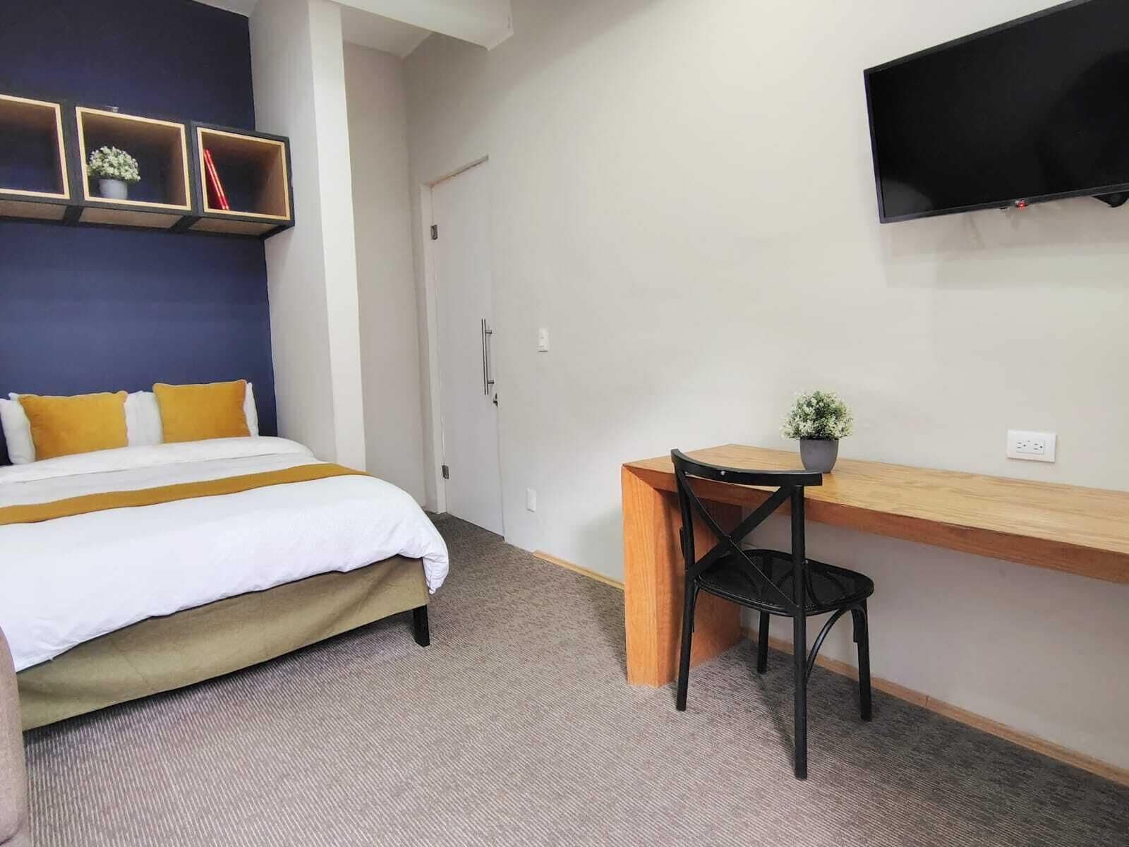 Ein Hotelzimmer mit Bett, Schreibtisch, Stuhl, Fernseher und einer Tür.