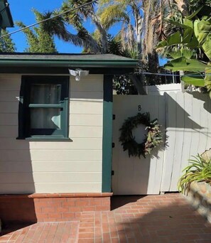 Charming single-story home with a welcoming atmosphere, featuring a wreath on the door and lush surroundings.