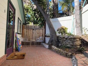 Enjoy a peaceful retreat in this serene outdoor space with a brick floor, wooden door, and a tree.