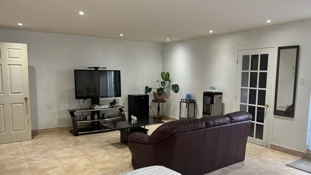 Una sala de estar con televisión, un sofá, una mesa de centro y un refrigerador.