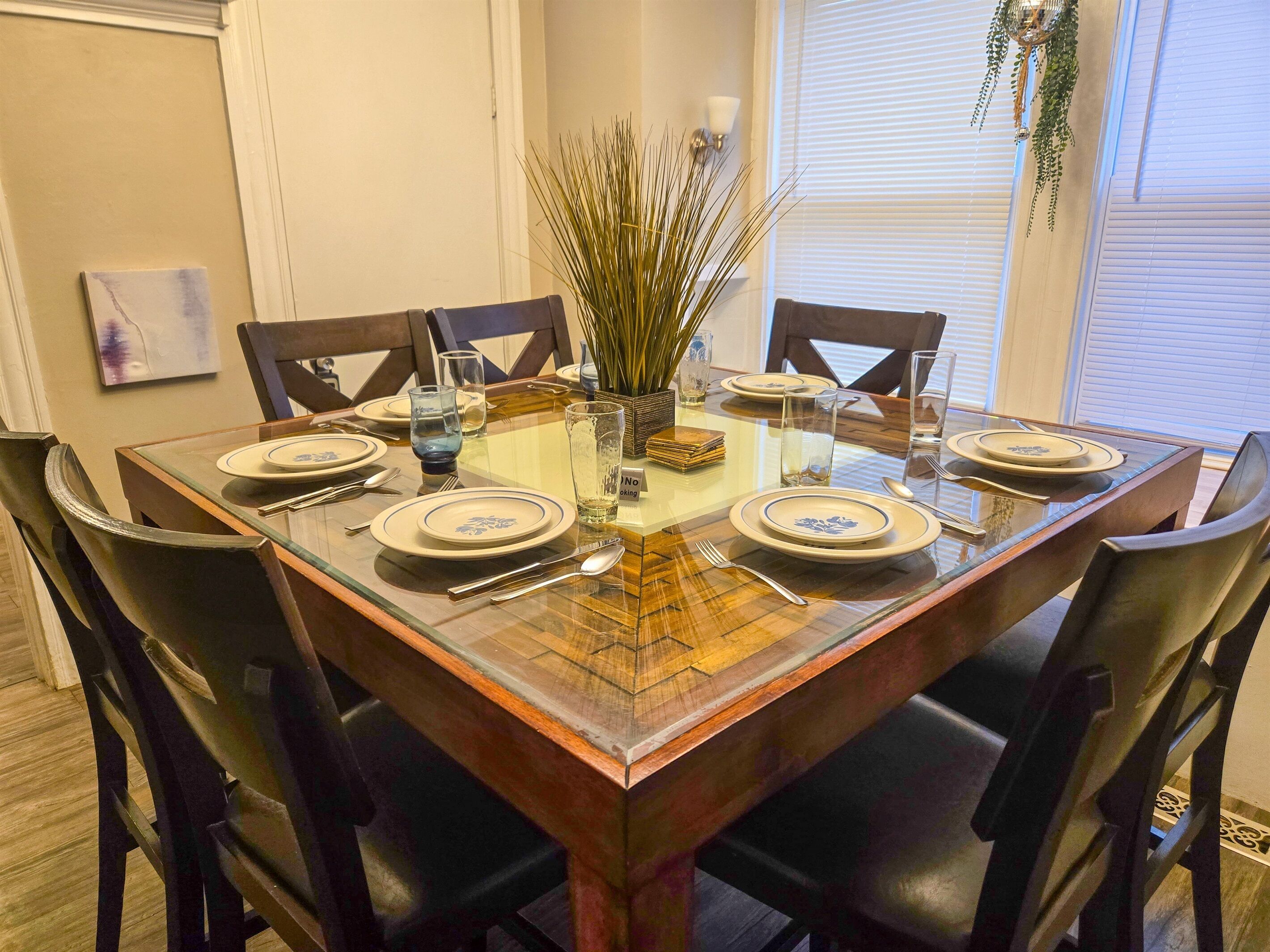 A dining table set for six with a glass top, surrounded by six chairs.