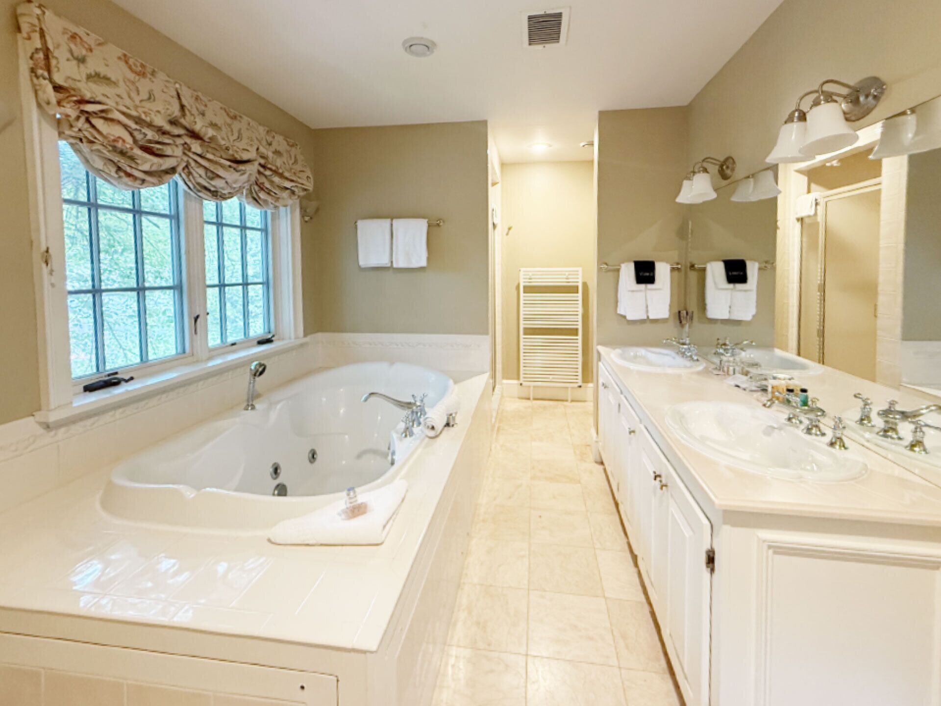 Une salle de bain spacieuse avec une grande baignoire îlot, deux lavabos et une douche à l’italienne.