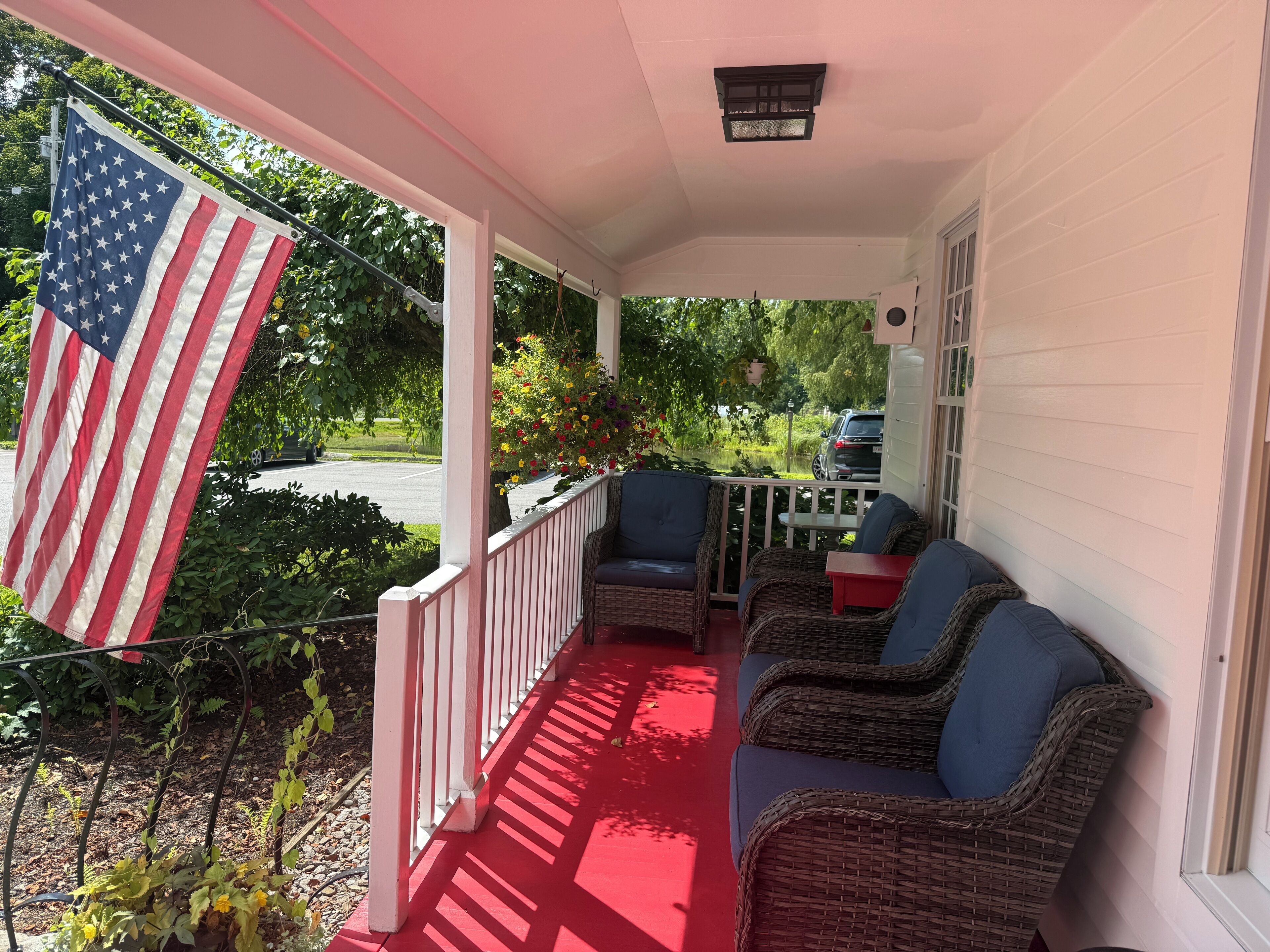 A porch with wicker furniture, a red carpet, and an American flag.