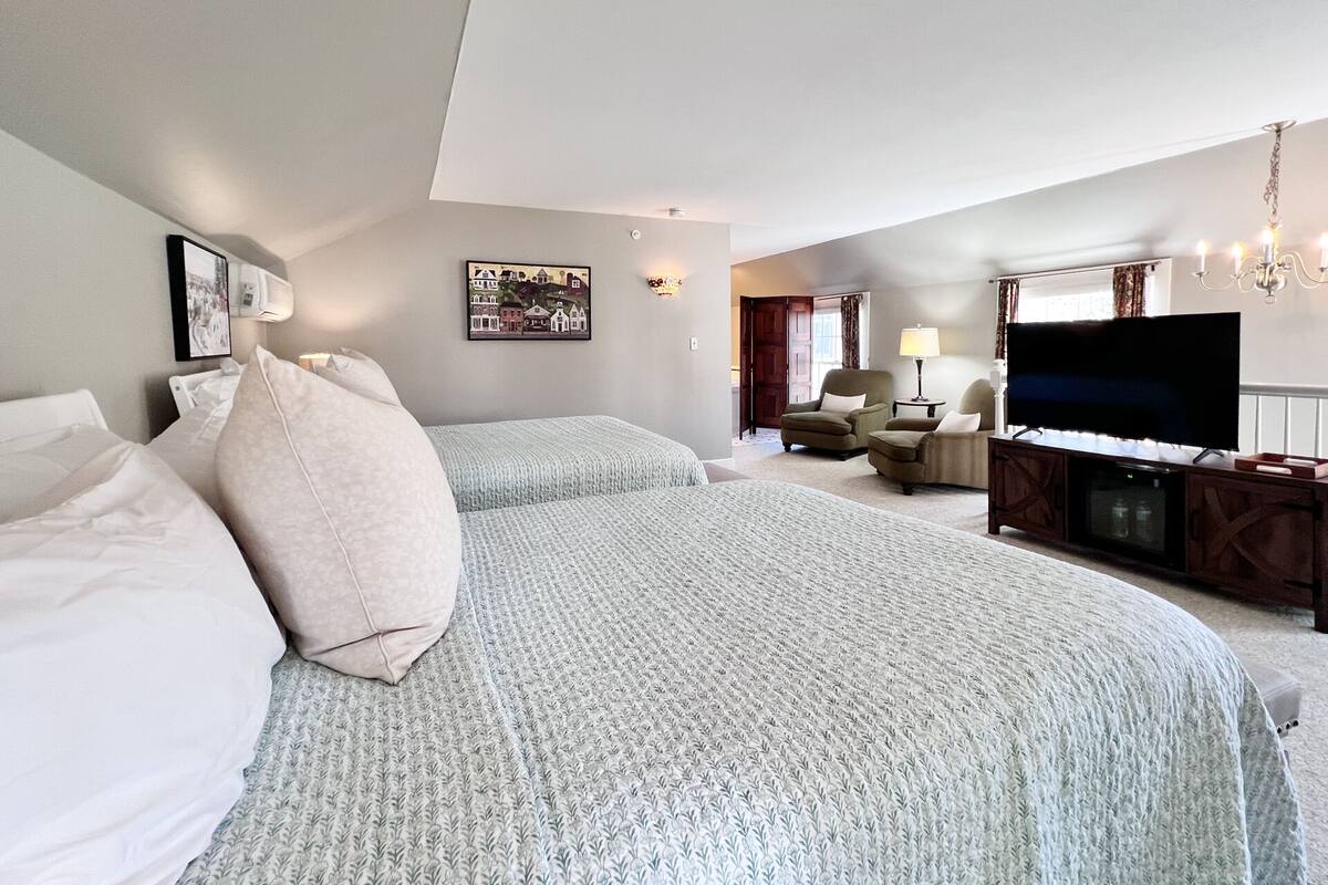 Una habitación de hotel con una cama grande, televisión, escritorio y una silla.