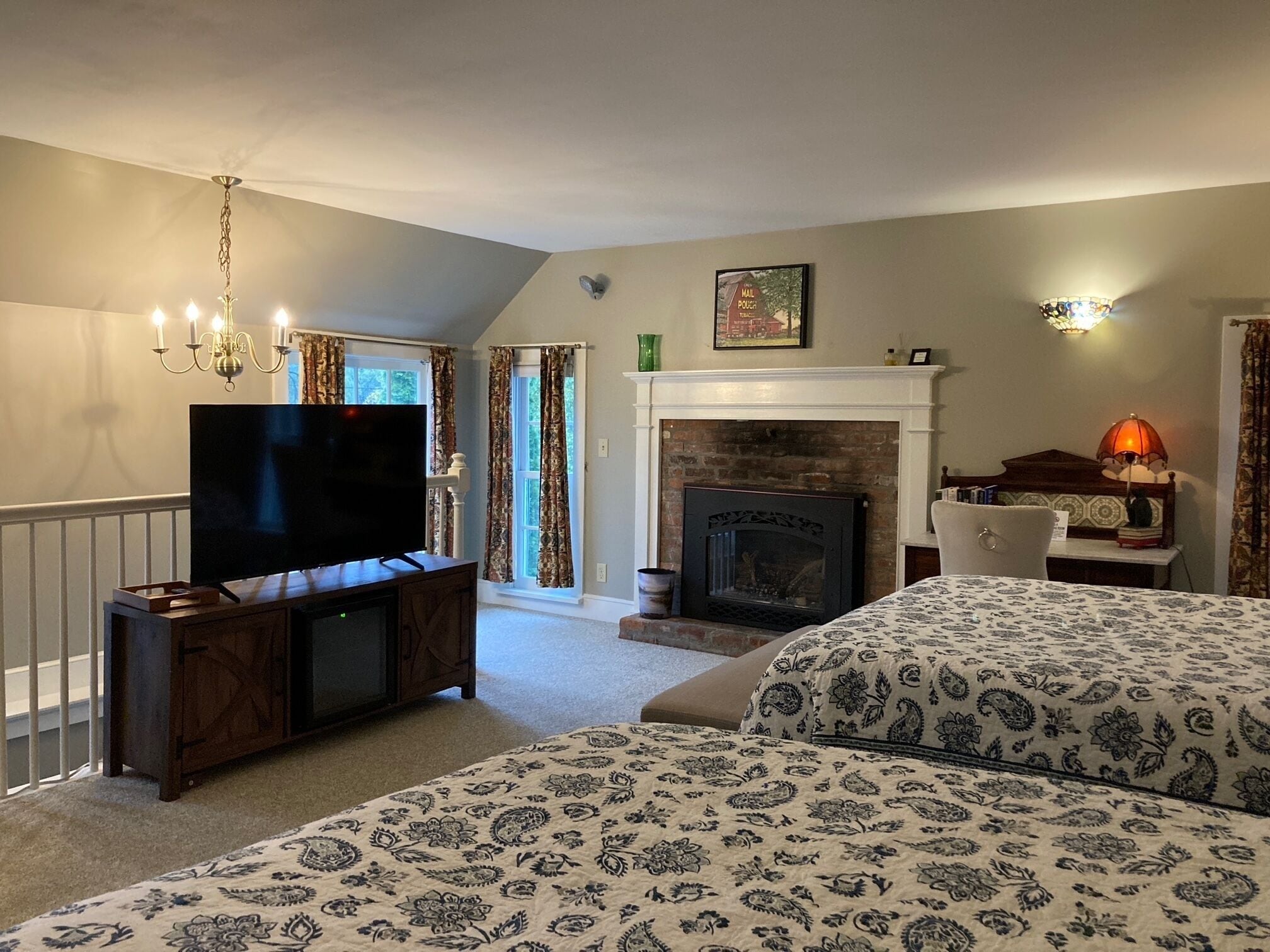 Een slaapkamer met een televisie, open haard en twee bedden.