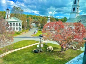 A historic building with a central tower, a parking lot, and a picnic area with benches.